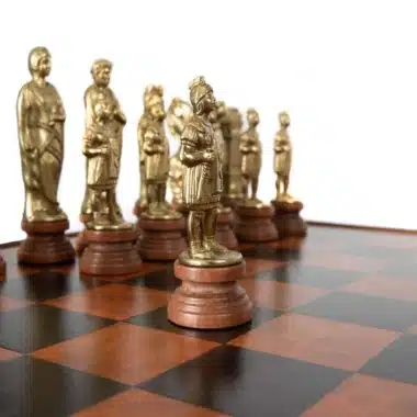 Goldene Schachfiguren im römischen Stil in einer Reihe auf dem Brett