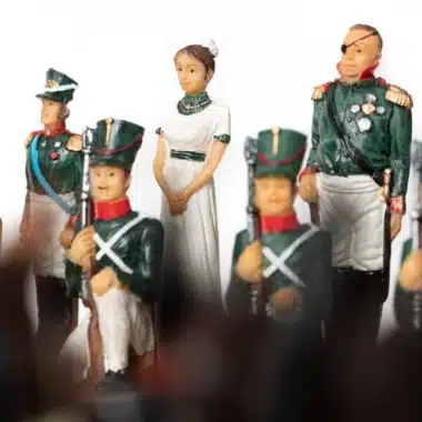 Schachfiguren mit Soldaten in grüner Uniform und Dame im weißen Kleid