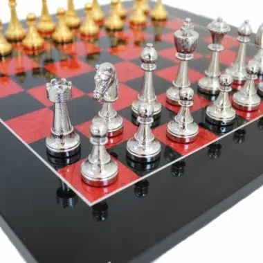 Versilberte Figuren des Fleuri-Sets aufgereiht auf dem schwarz-roten Schachbrett