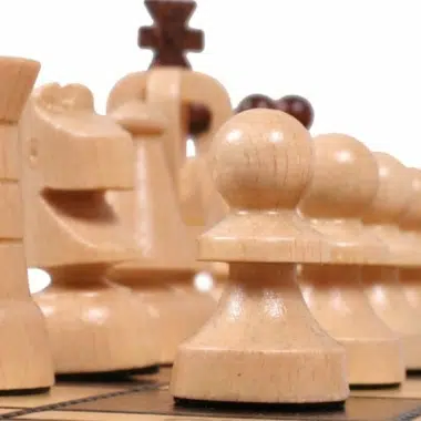 Schachfiguren aus Holz, Detail von Springer und aufgereihten Bauern auf dem Brett