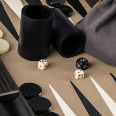Würfelbecher aus Holz und Stoffbeutel auf dem Backgammon-Brett