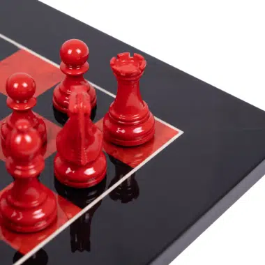 Nahaufnahme der rot lackierten Schachfiguren und der Spiegelglanzoberfläche des Schachbretts