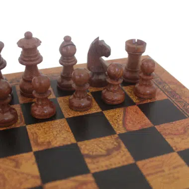 Nahaufnahme der dunklen Schachfiguren aus Akazienholz auf einem Brett mit Vintage-Weltkartenmuster